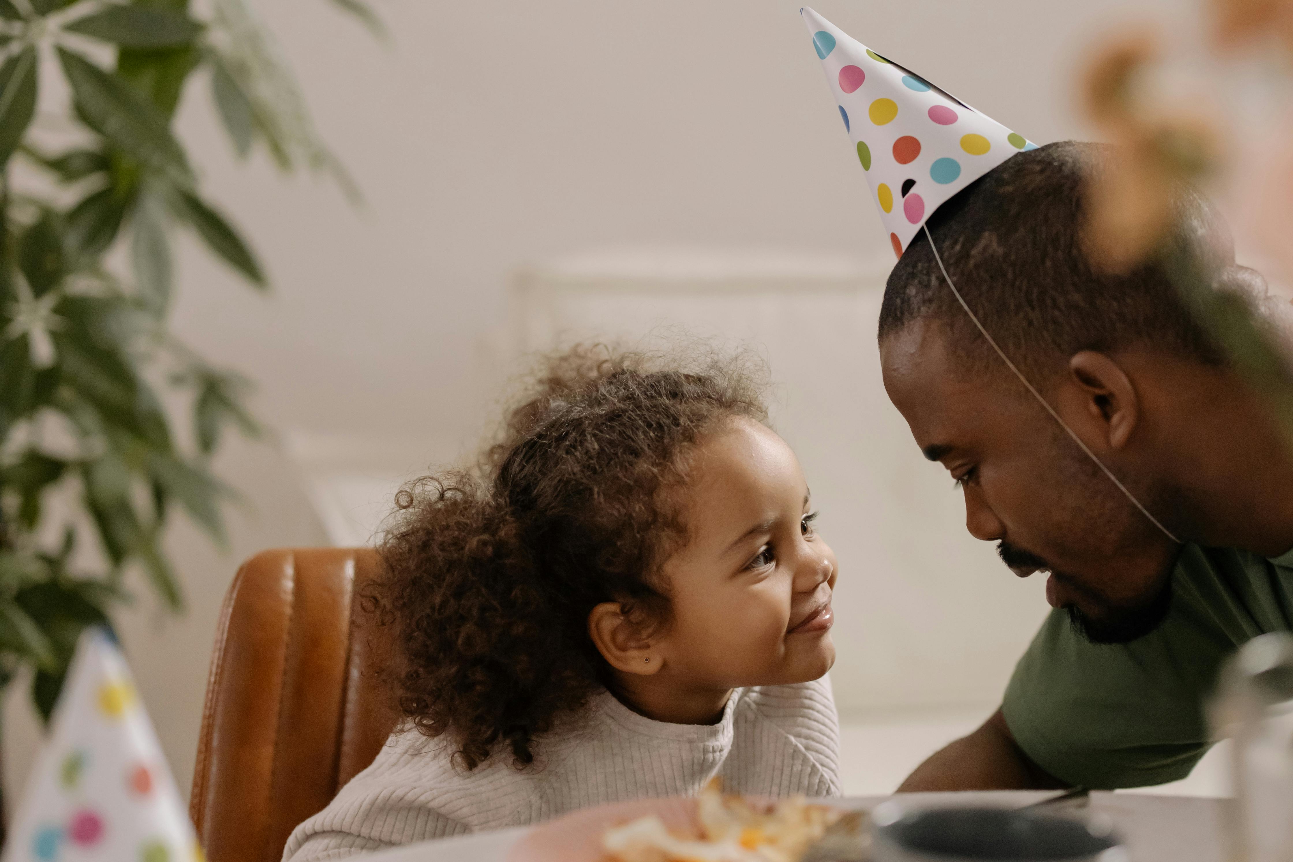 A Man Talking to His Daughter while Wearing a Party Hat · Free Stock Photo