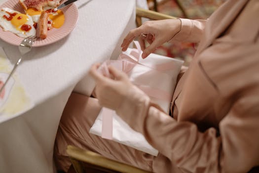 Woman enjoying a breakfast with sunny side up eggs while unwrapping a gift at a cozy table.