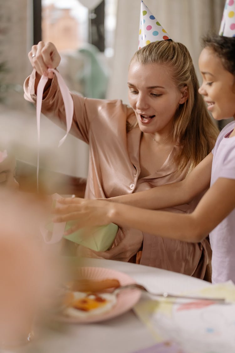 A Woman In Pink Long Sleeves Opening Gift With Her Daughter