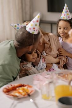 A joyful family celebration with children wearing colorful party hats indoors.