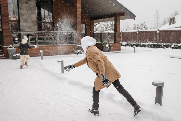 Back View Of Two People Playing In The Snow