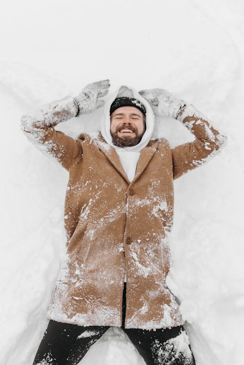 A Bearded Man in Winter Clothes Lying on a Snow Covered Ground