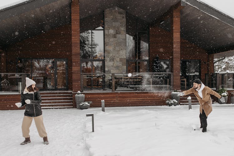 A Couple Playing Snow In Front Of Their House