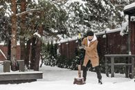 Child in Orange Jacket and Black Pants Standing on Snow Covered Ground