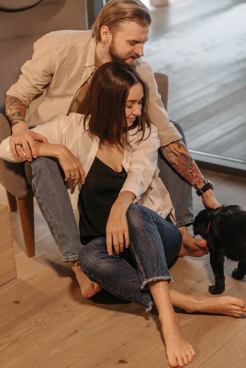 Free A couple shares a warm moment with their dog at home, embodying love and comfort. Stock Photo