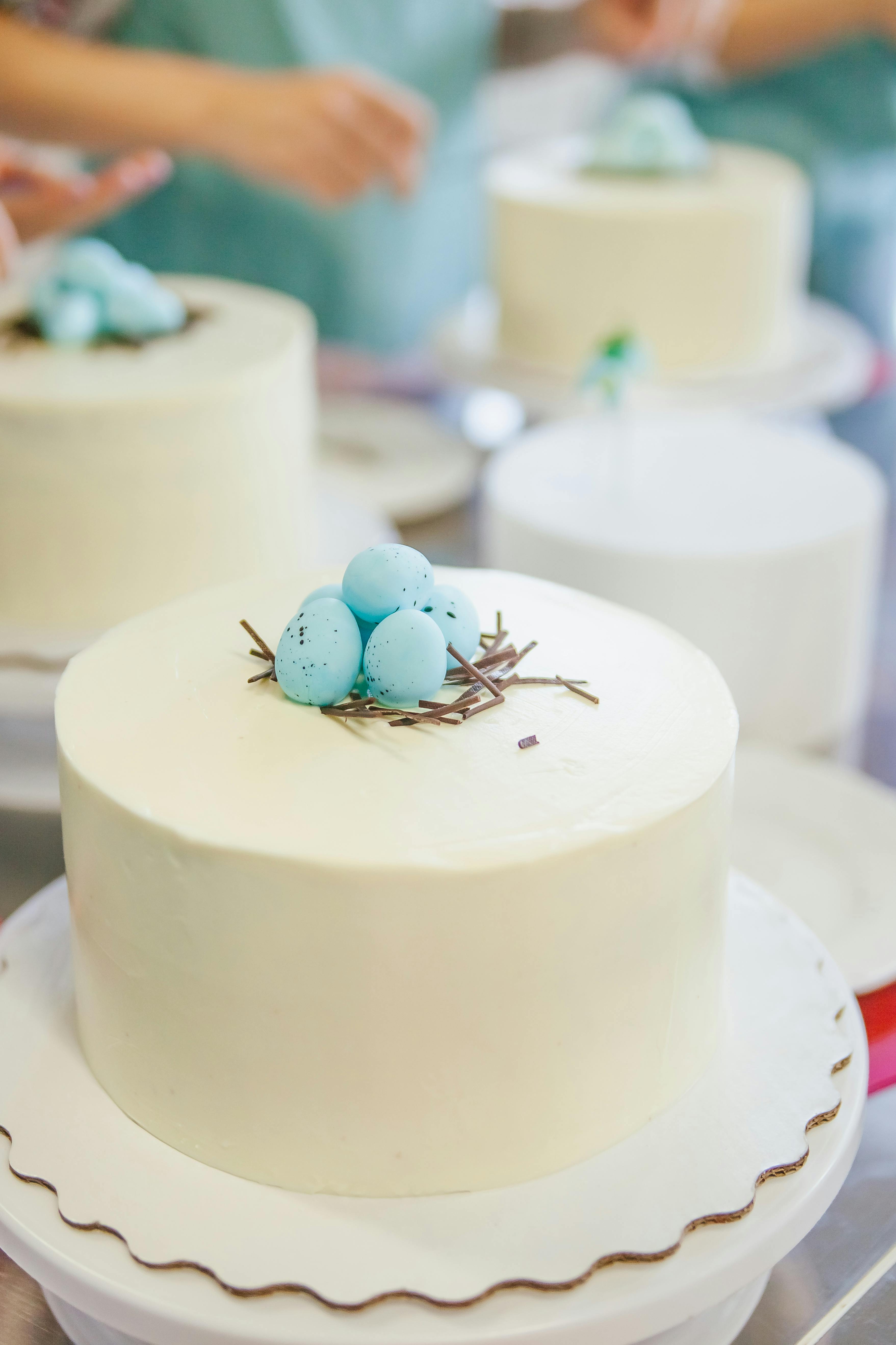 Free Minimalist white cake adorned with blue sugar eggs, perfect for Easter celebrations. Stock Photo