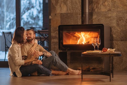 Man and Woman Sitting on the Floor Near Fireplace