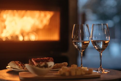 Free Intimate dining by the fireplace with wine and appetizers, perfect for a cozy winter evening. Stock Photo