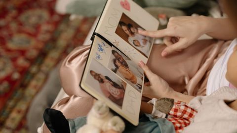A child and parent bonding over a family photo album indoors.