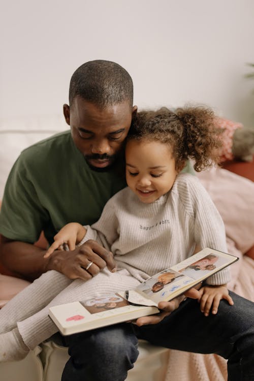 Photograph of a Child and Her Father Looking at a Photo Album