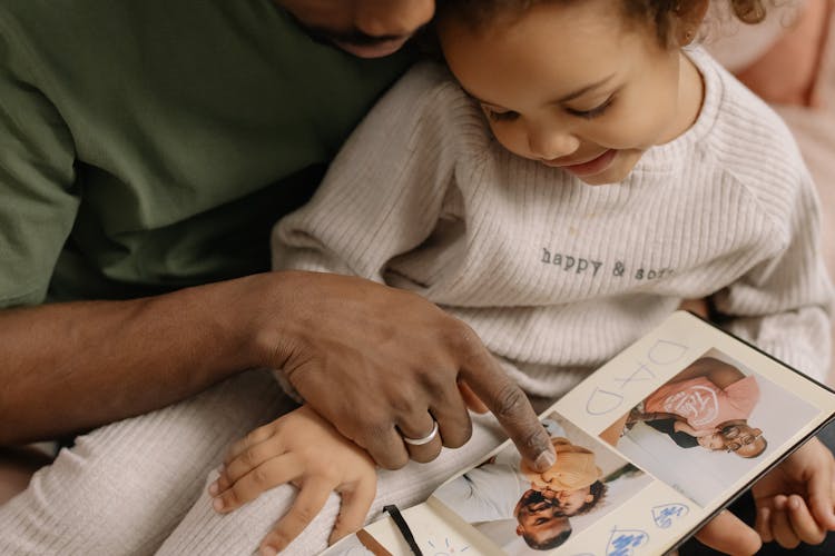 Smiling Daughter And Father Watching Pictures