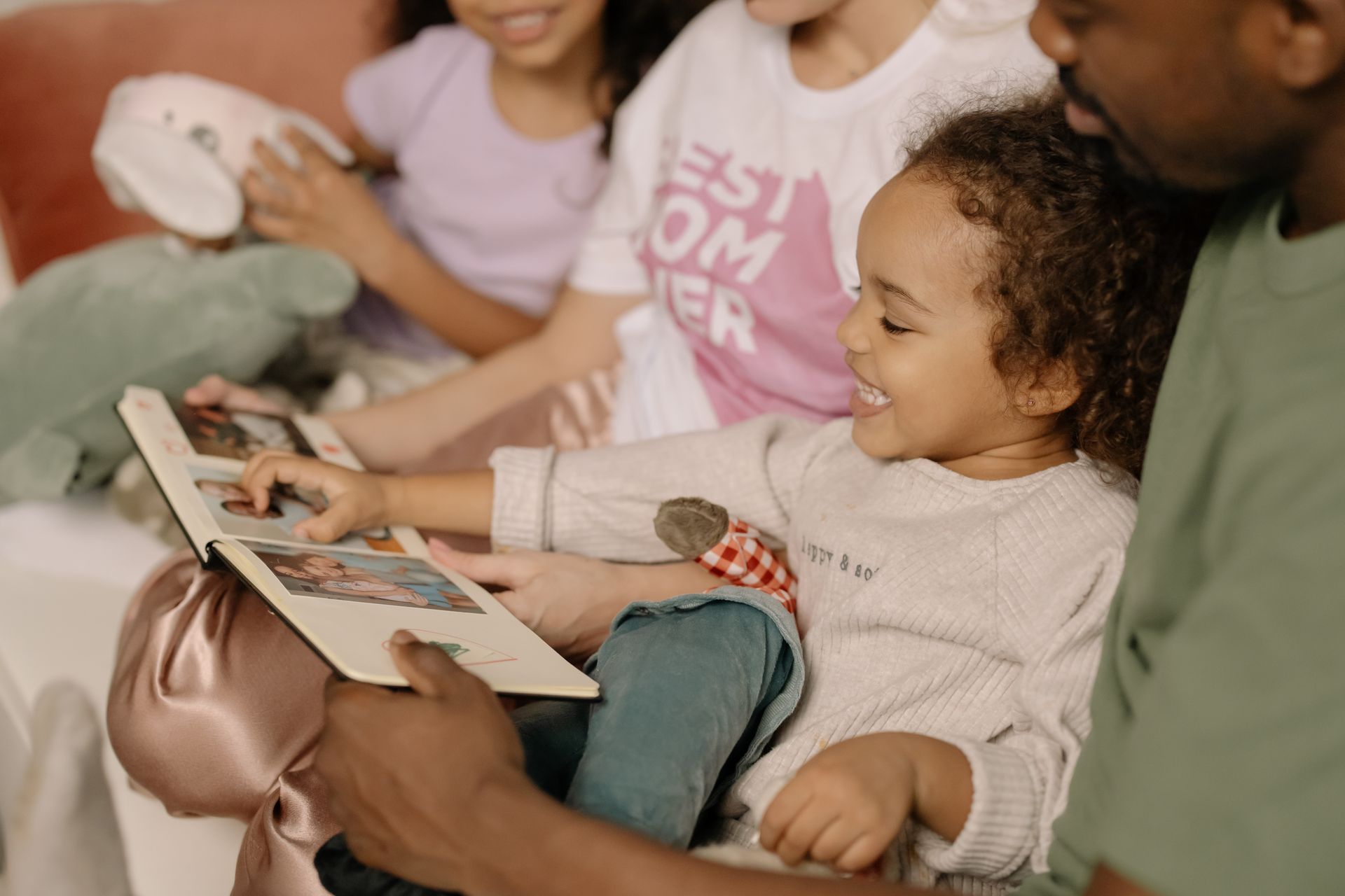 A diverse family sharing joyful moments while looking at a photo album indoors.