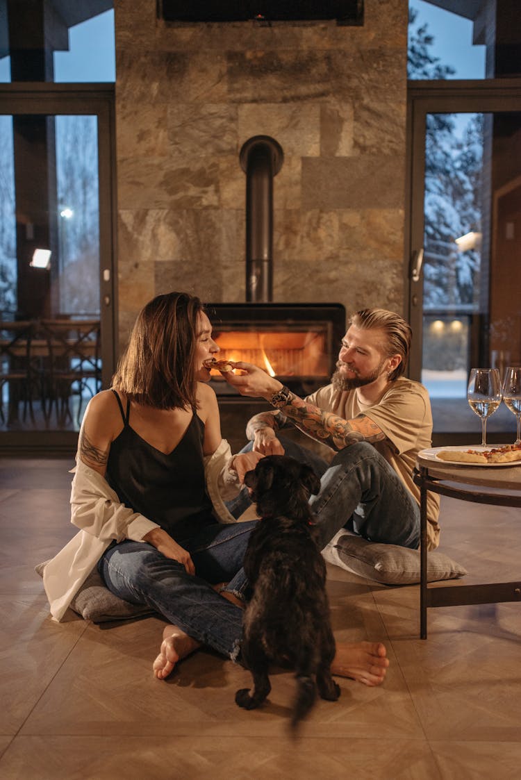 A Couple Sitting On The Floor While Eating Food