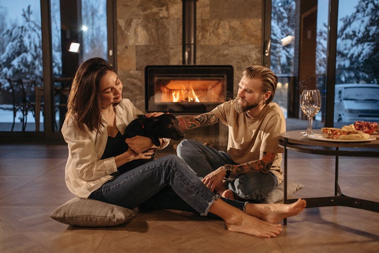 Man And Woman Sitting On Floor Beside Fireplace