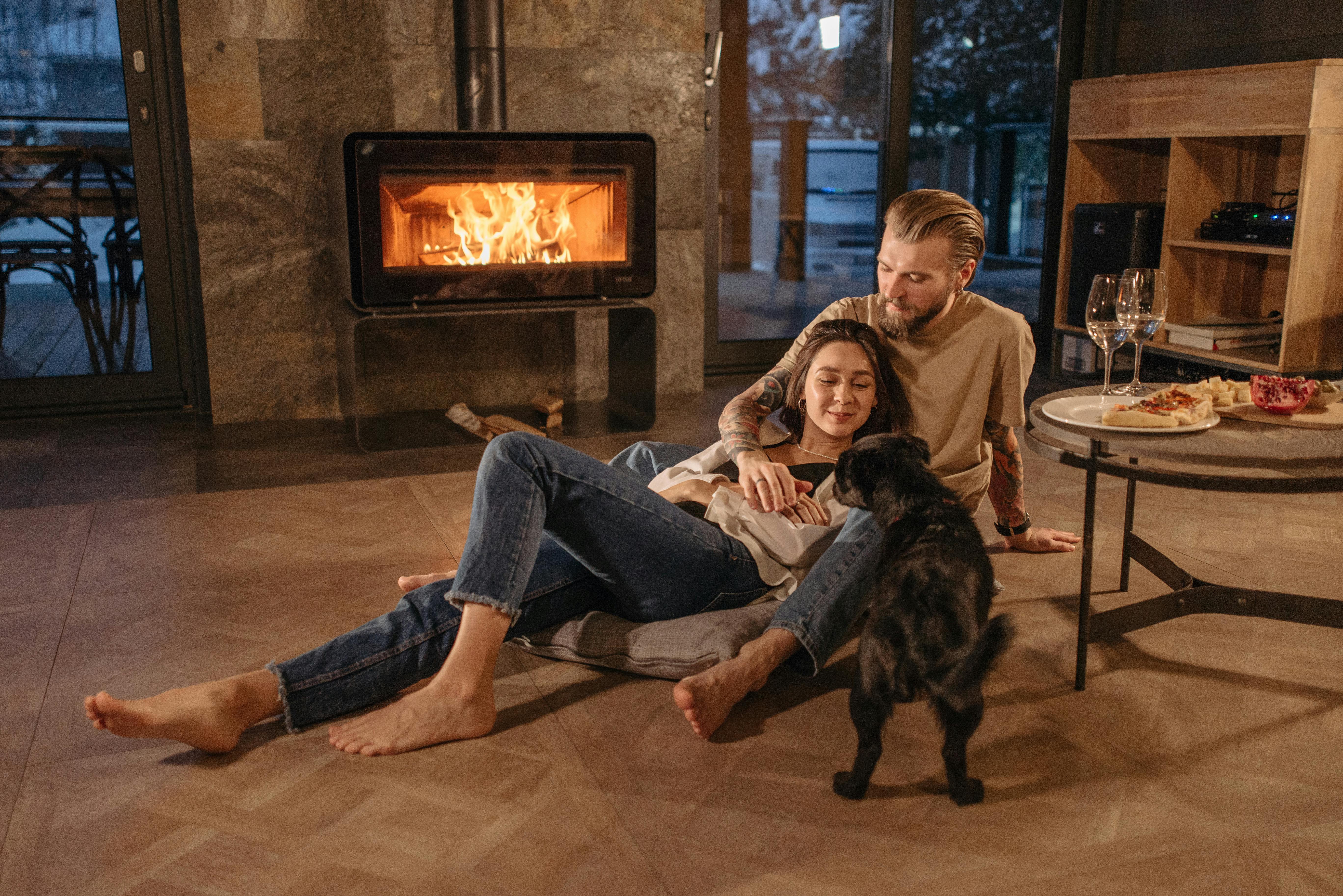 Couple with a Dog Sitting Beside the Fireplace · Free Stock Photo