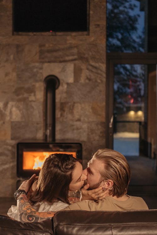 Photograph of a Man and a Woman Kissing Near a Fireplace