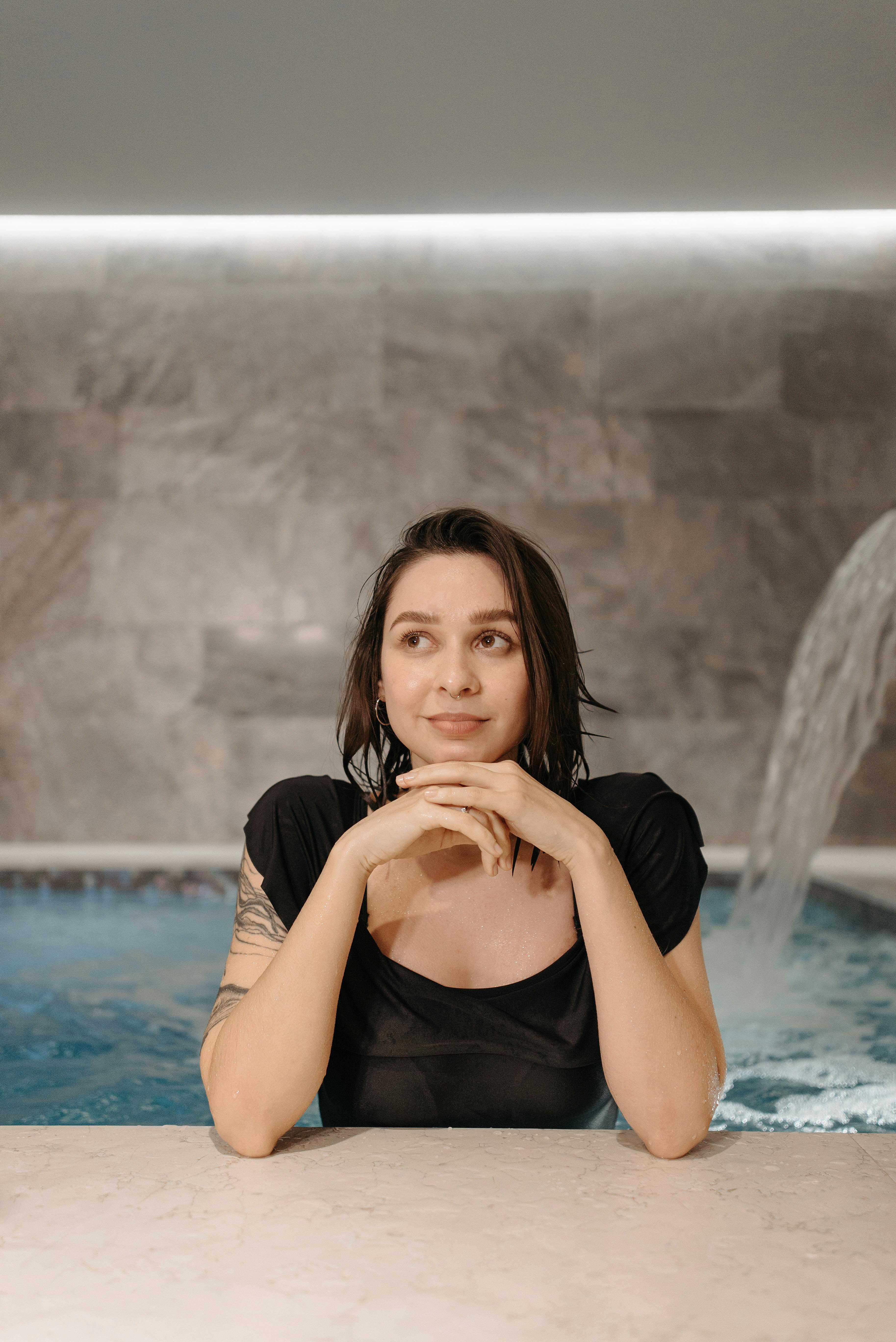 woman in black tank top sitting on swimming pool