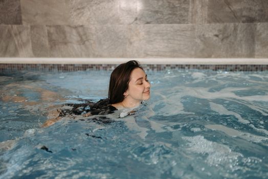 Woman swimming comfortably in an indoor pool, enjoying a peaceful moment.