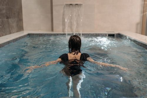 Free A woman enjoying a swim in an indoor pool with a waterfall feature. Stock Photo