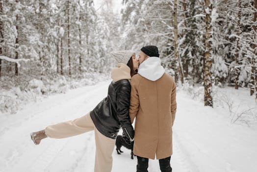 Couple kissing in a snow-covered forest, expressing warmth and affection during winter.