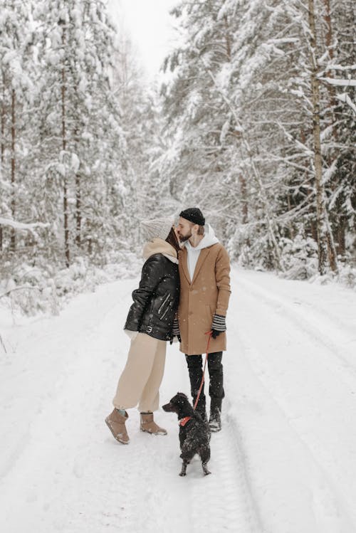 A Couple Kissing while Standing on a Snow Covered Pathway