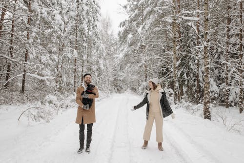 A Couple on a Snow Covered Pathway with Their Pet Dog