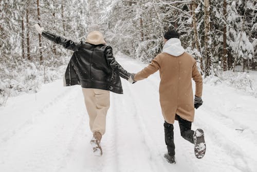 Back View of a Couple Walking on the Snow while Holding Hands