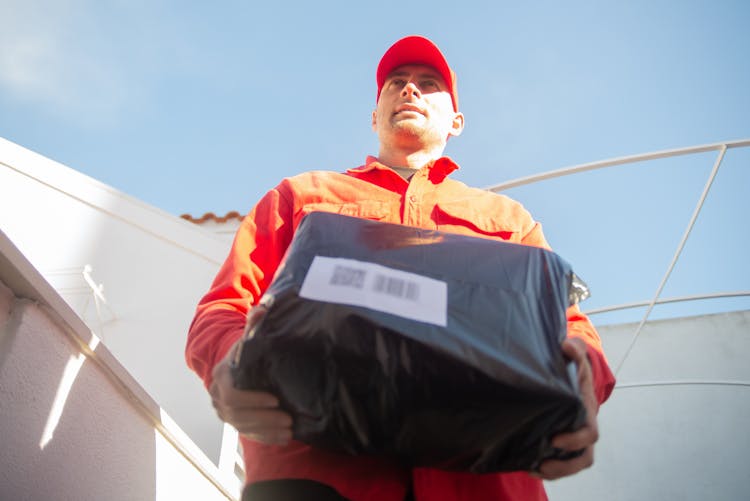 Low-Angle Shot Of A Delivery Man Holding A Black Parcel