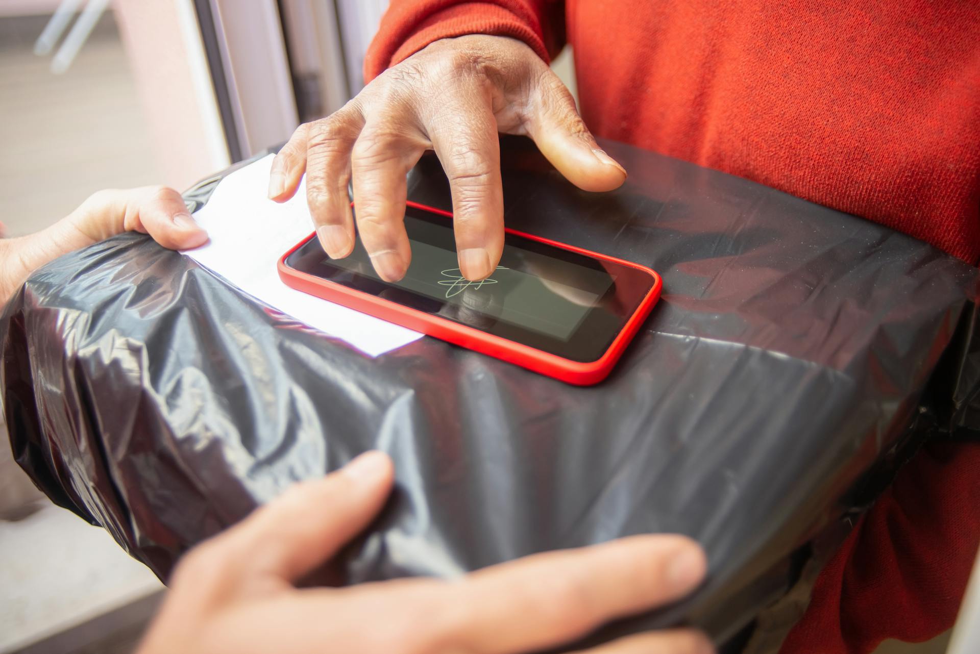 Close-up of a person signing for package delivery on touchscreen device.