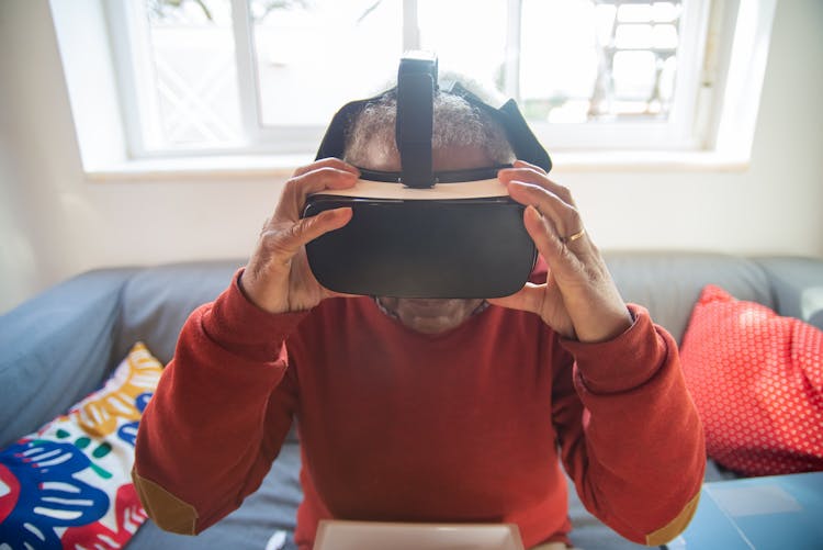 A Man In Red Sweater Wearing VR Headset While Sitting On A Couch