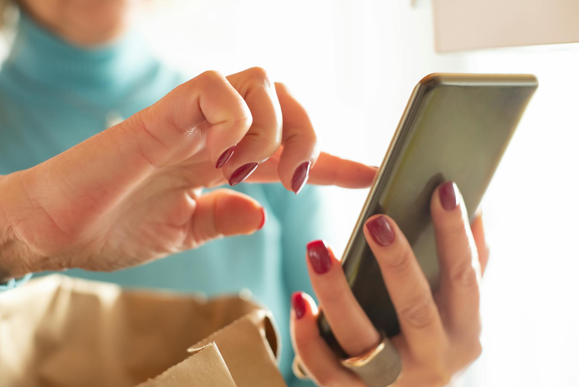 Hands interacting with a smartphone screen indoors, showcasing modern technology and connectivity.