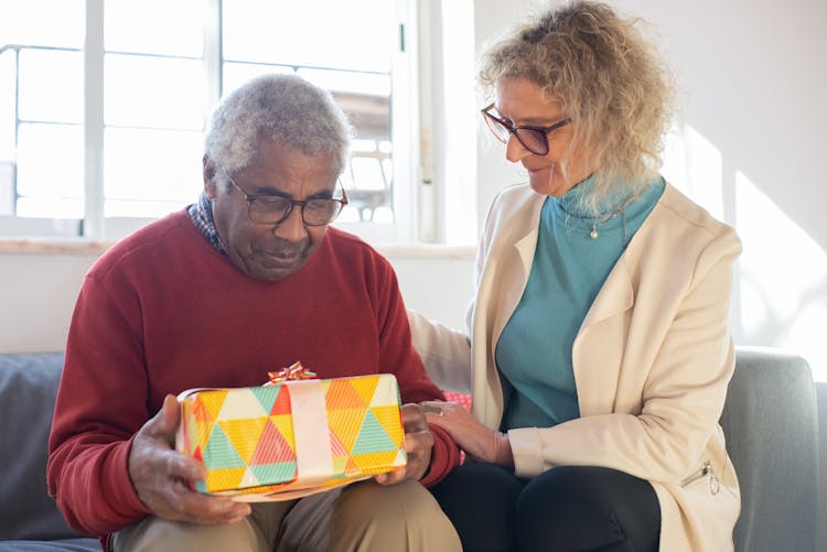 Elderly Man Holding A Gift Beside A Woman