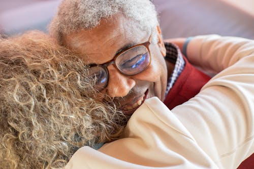 Free Close-Up Photo of a Man with Gray Hair Hugging Another Person while Smiling Stock Photo
