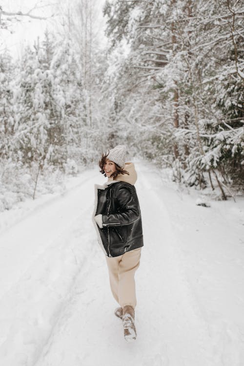 Smiling Woman in Jacket on Dirt Road in Forest in Snow
