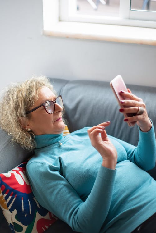 Woman Relaxing on Sofa Using Smartphone