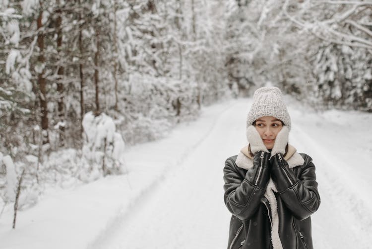 A Woman In Black Leather Winter Jacket With Gloves Holding Her Cheeks