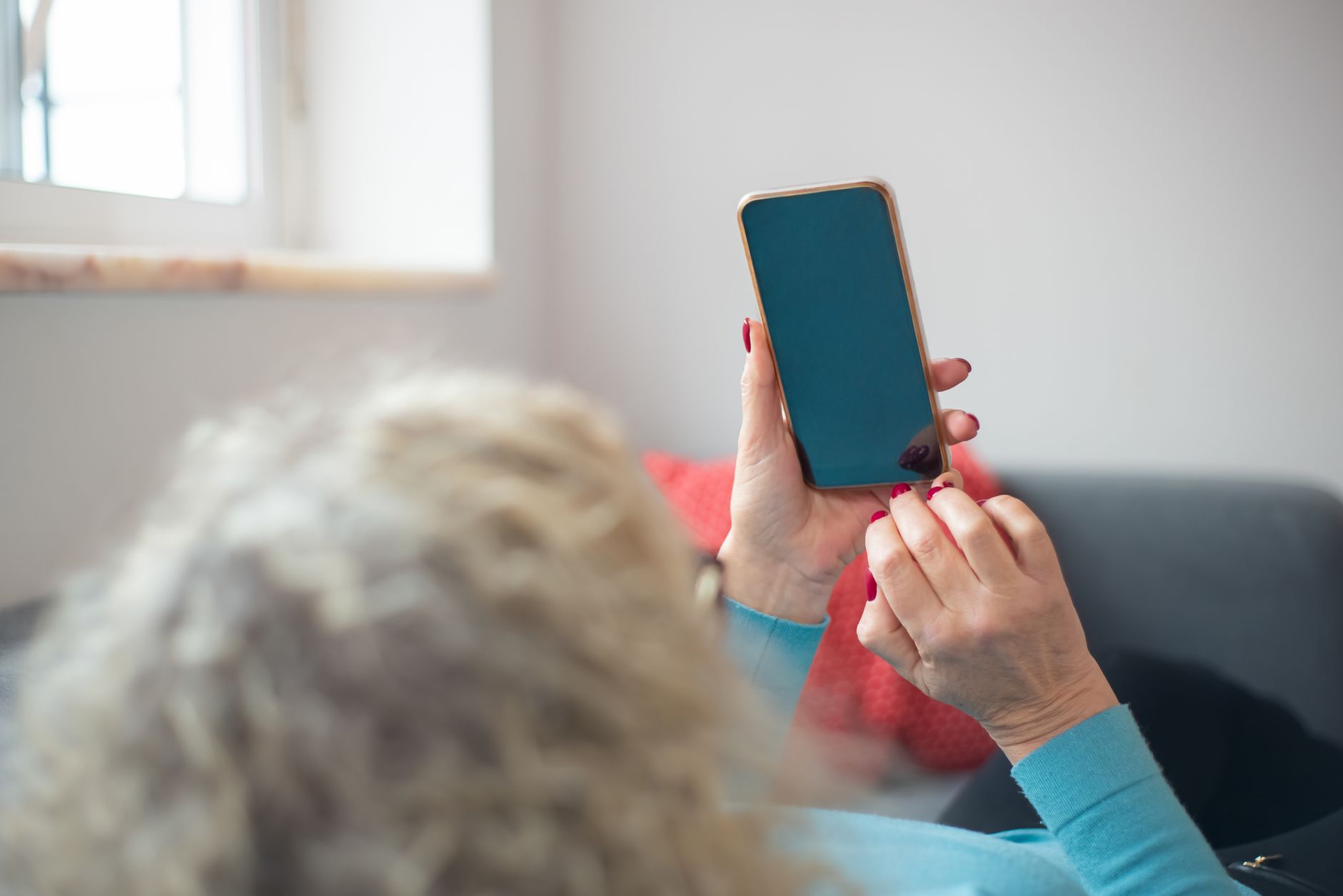 전남 어르신 스마트폰 무료 교육, 섬·농촌 지역까지 무료 교육 찾는 법 6 Elderly woman with smartphone lying on a couch indoors, relaxed and comfortable.