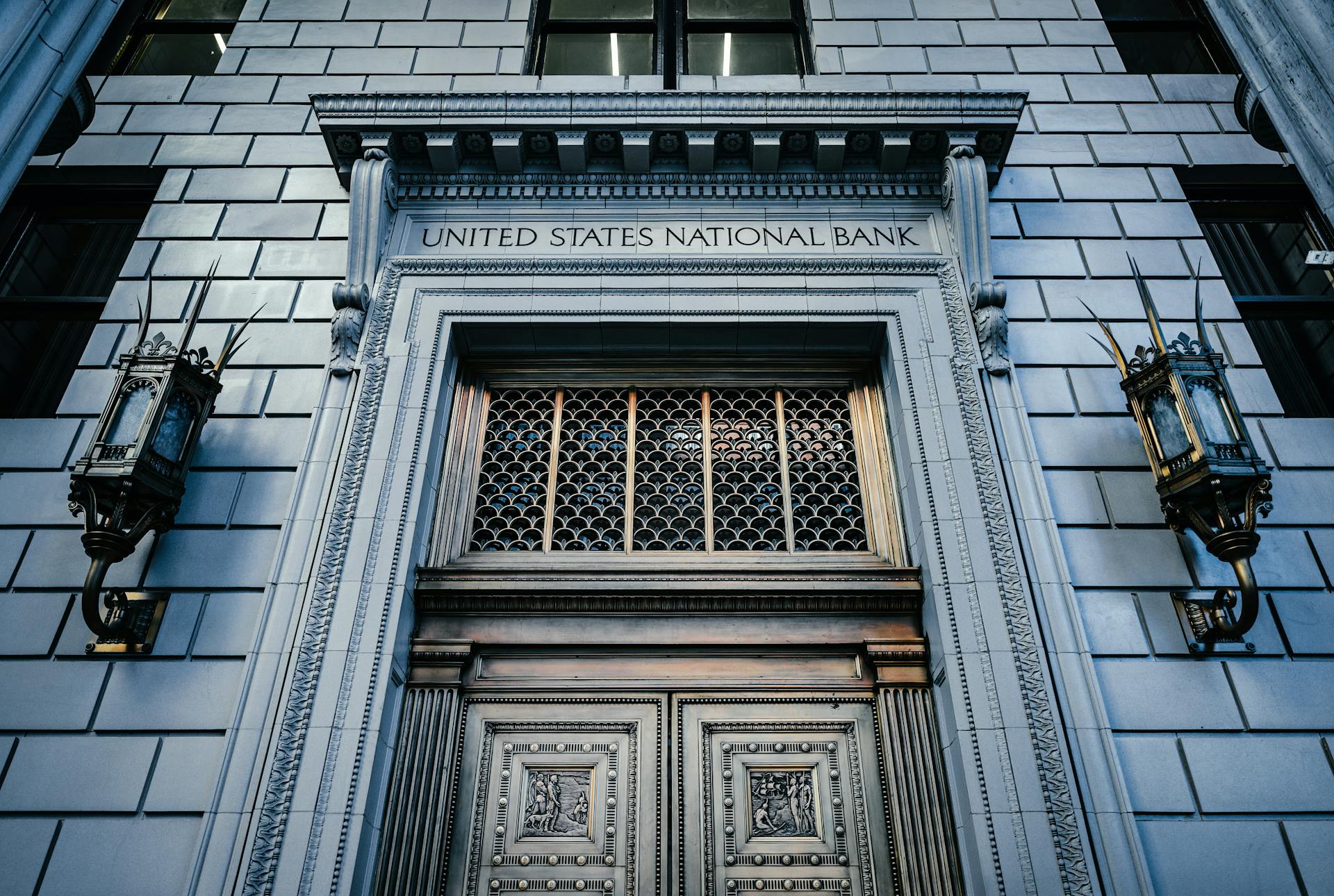 From below classic styled historic building of United States National Bank with wooden doors and vintage lanterns located in Portland