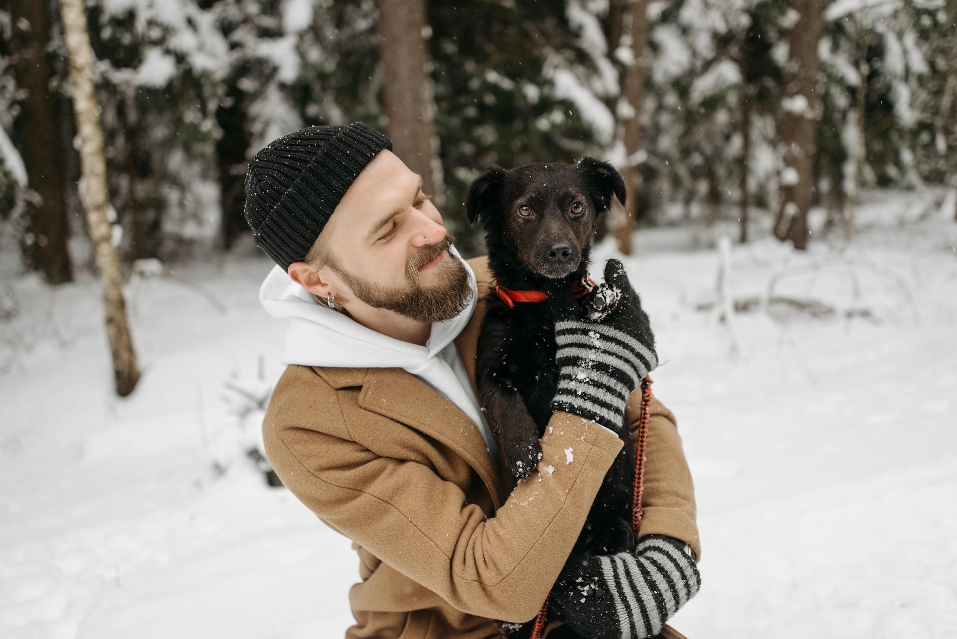 A Man Wearing Winter Clothes Carrying His Dog