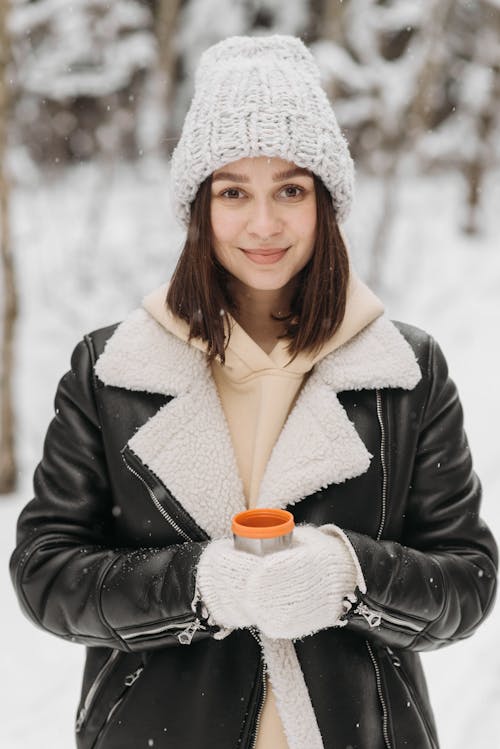 Woman in Black Winter Jacket and Knit Hat Holding a Cup