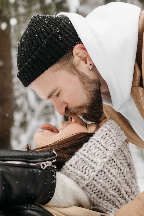 Free Photo of a Man with a Black Knitted Cap Kissing a Woman on the Nose Stock Photo