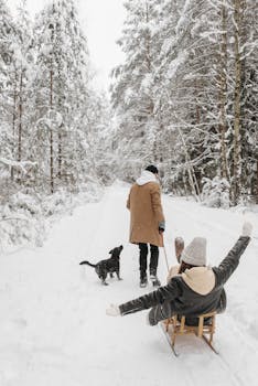A couple enjoying a winter day in a snowy forest with their dog and sleigh.