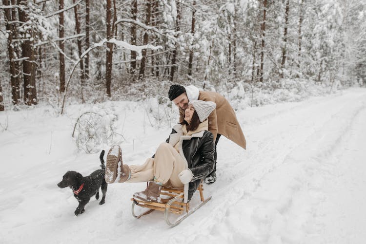 
A Man Pushing A Woman On A Sleigh