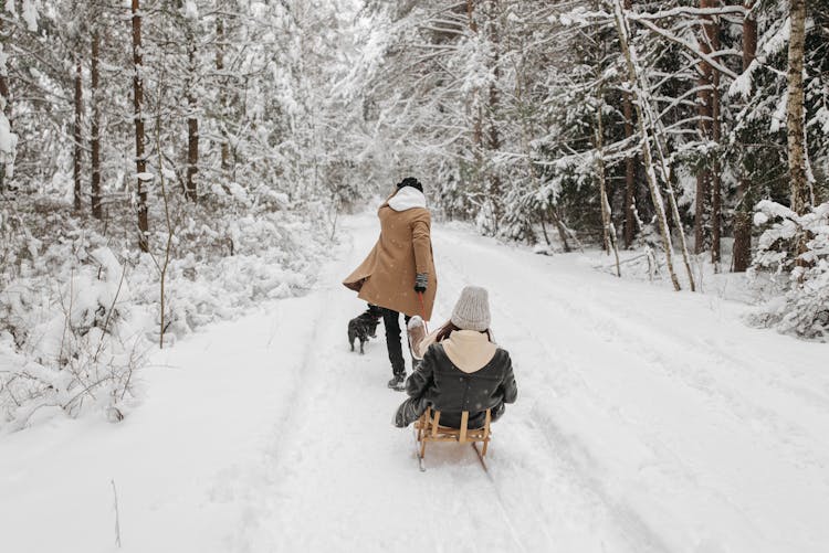 
A Man Pulling A Woman On A Sleigh