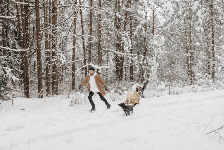 
A Man Pulling A Woman On A Sleigh