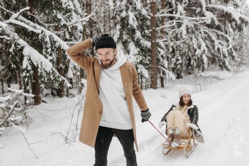 Free A joyful couple experiencing a fun sleigh ride through a snow-covered forest in winter. Stock Photo