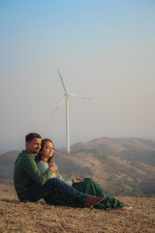 Photograph of a Couple Sitting Near a White Windmill