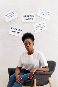 Young woman sitting in chair with motivational health posters behind her.