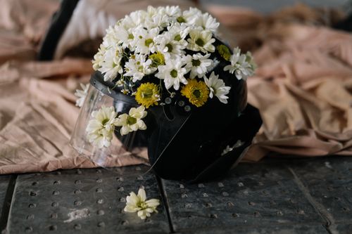Free A black helmet creatively decorated with white and yellow flowers indoors. Stock Photo