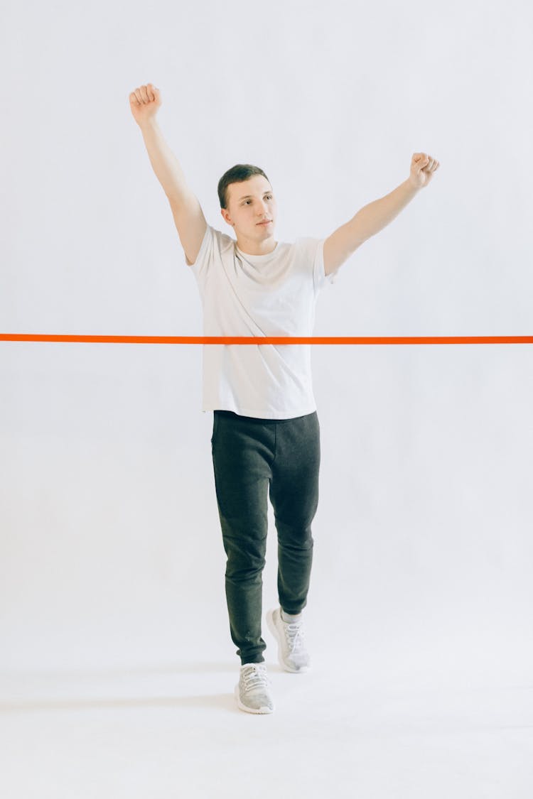 Man In White Crew Neck Shirt And Black Pants Raising His Arms 